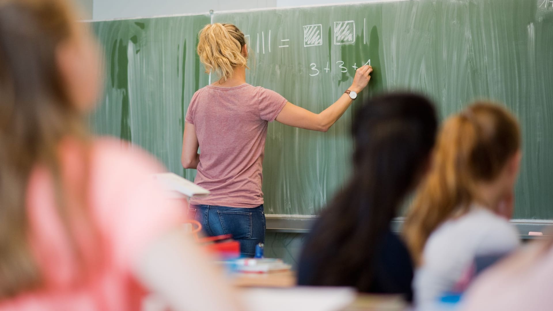 Eine Lehrerin schreibt etwas an die Tafel (Symbolbild): In Niedersachsen besteht an Haupt- und Realschulen Lehrermangel.