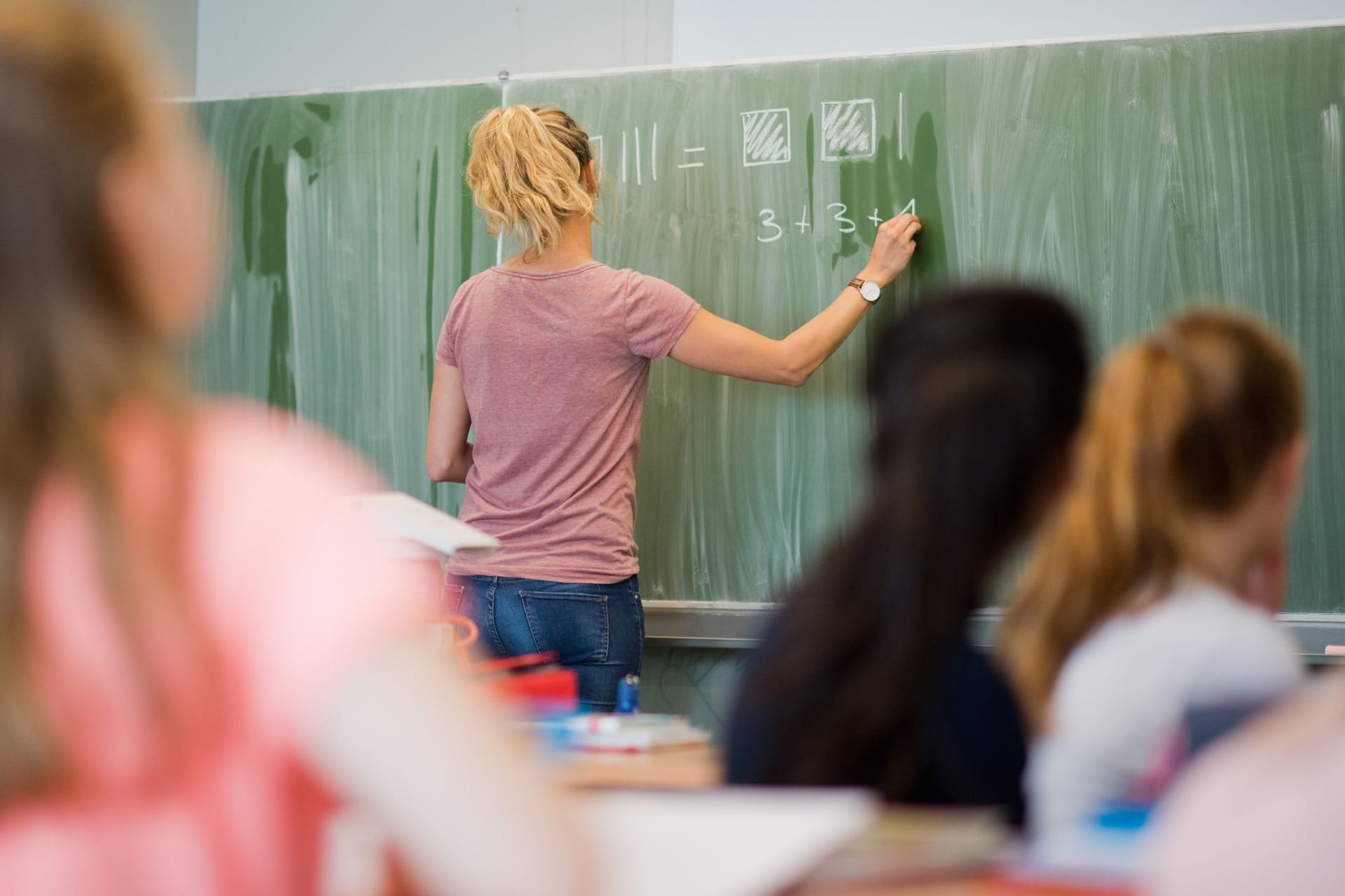 Eine Lehrerin schreibt etwas an die Tafel (Symbolbild): In Niedersachsen besteht an Haupt- und Realschulen Lehrermangel.