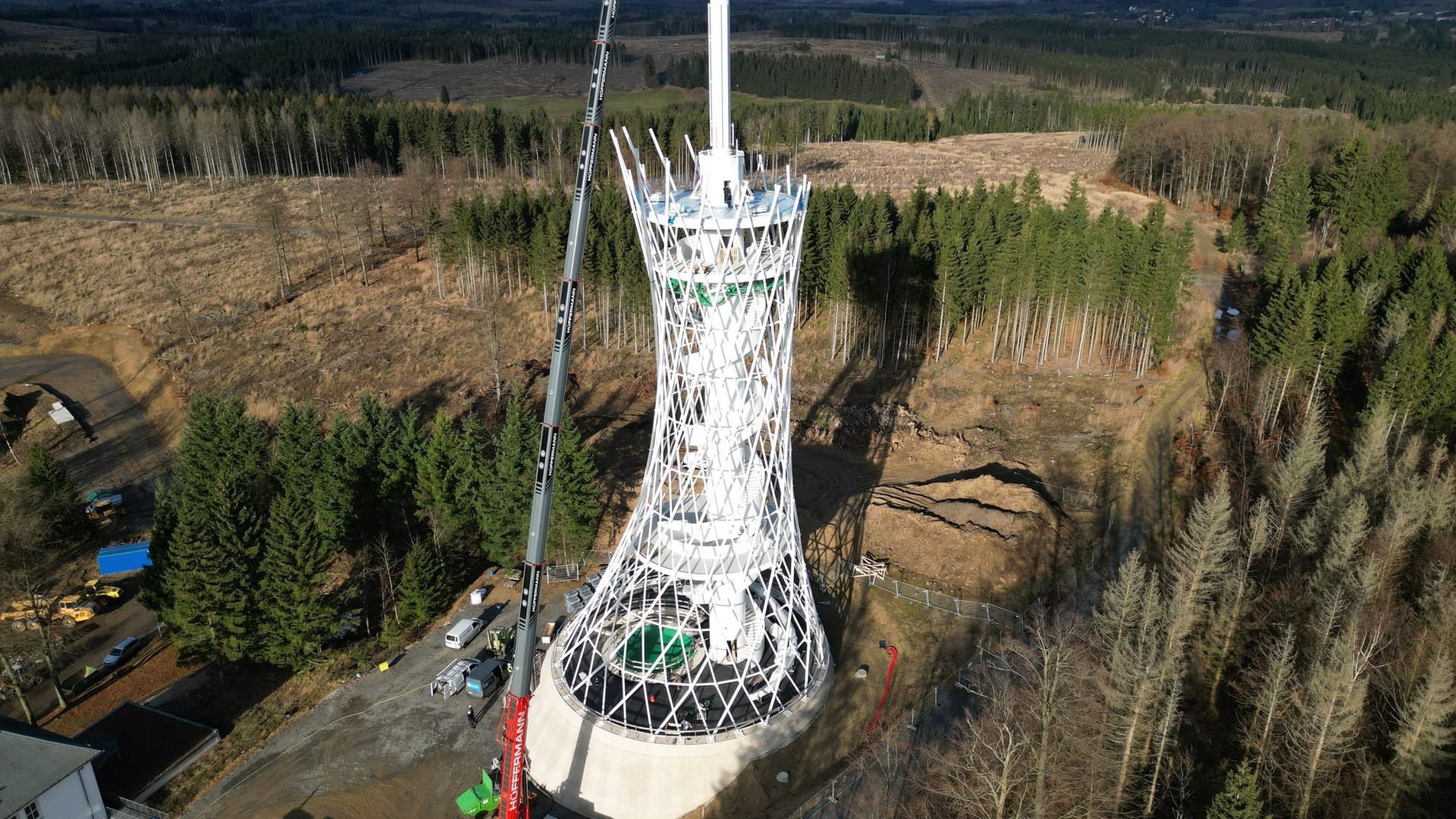 Mit einer Drohne aufgenommen: Mit einem Kran werden die Einzelteile des 25 Meter langen Besenstiels auf dem Aussichtsturm am Harzer Hexenreich aufgesetzt.