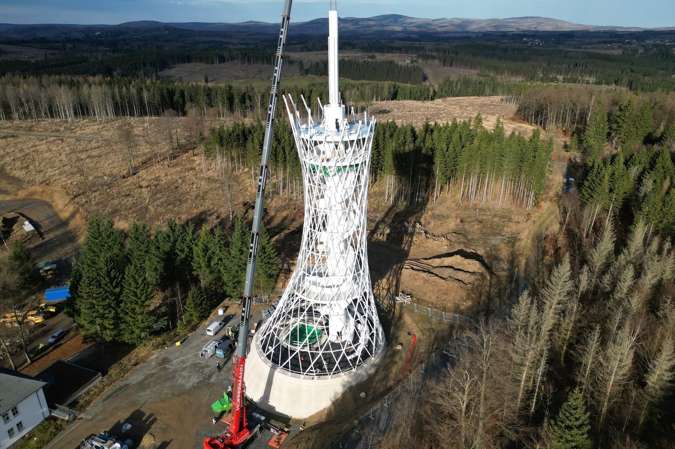 Mit einer Drohne aufgenommen: Mit einem Kran werden die Einzelteile des 25 Meter langen Besenstiels auf dem Aussichtsturm am Harzer Hexenreich aufgesetzt.