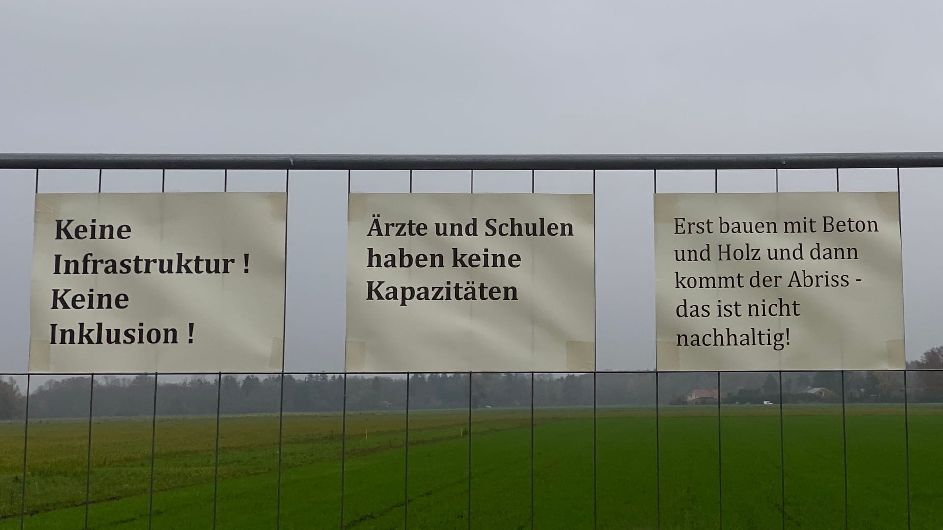 Ihre Argumente gegen den Bau der Flüchtlingsunterkunft haben die Bürgerinnen und Bürger auf Zettel geschrieben und diese an einen Zaun vor der betroffenen Fläche gehängt.