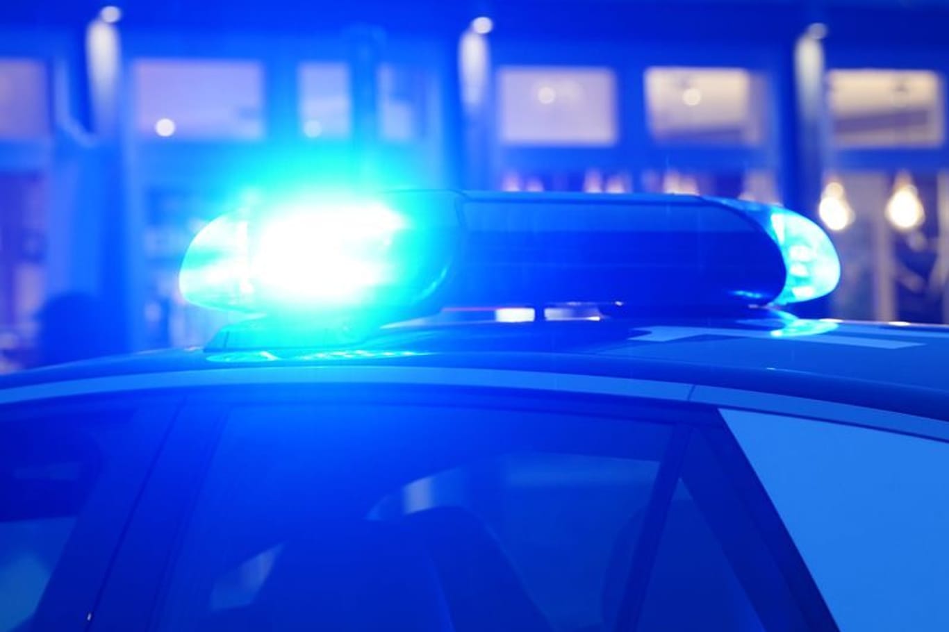 Ein Streifenwagen der Polizei steht mit eingeschaltetem Blaulicht an einem Einsatzort.