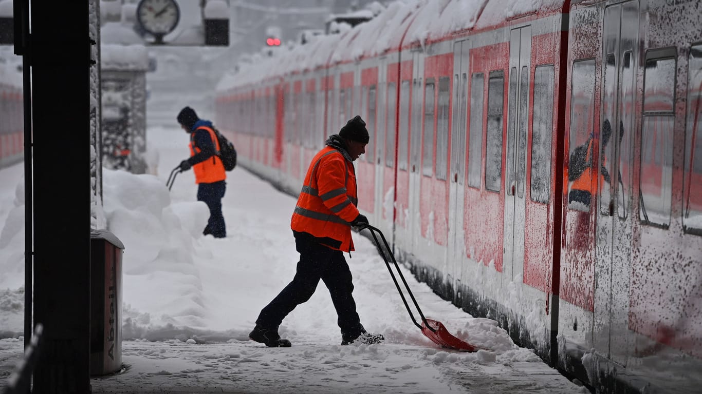 Arbeiter räumen auf dem Bahnsteig am Münchner Hauptbahnhof Schnee (Archivbild):