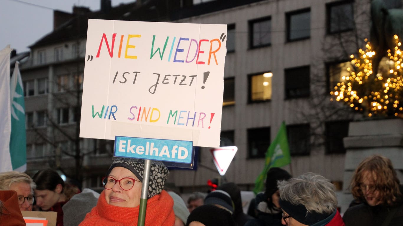 Eine Frau hält ein buntes Protest-Plakat, das sich gegen die AfD richtet.