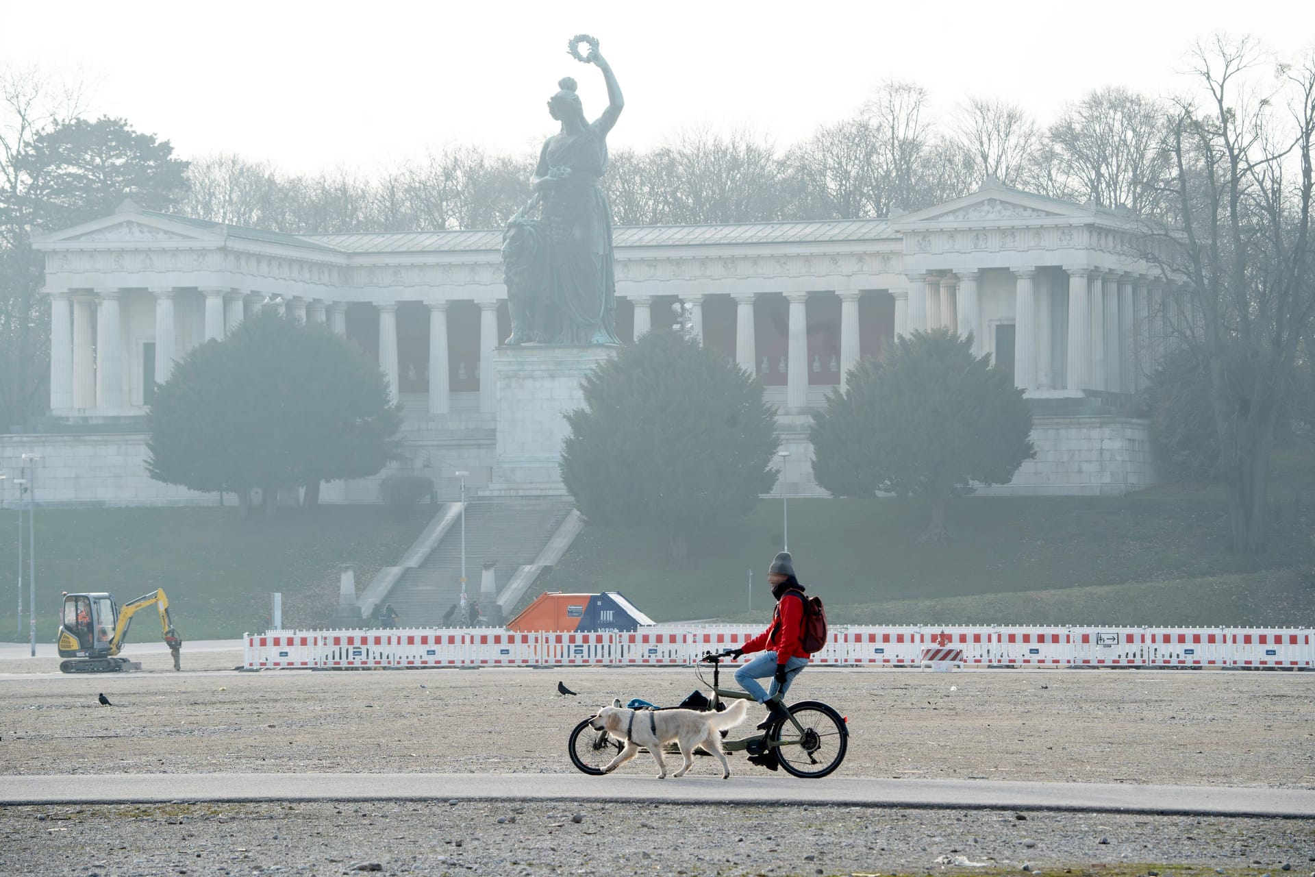 Ein Mann fährt mit seinem Fahrrad vor der Bavaria auf der Theresienwiese (Archivbild): Die Sonne hat es am Dienstag schwer, sich gegen den Nebel durchzusetzen.