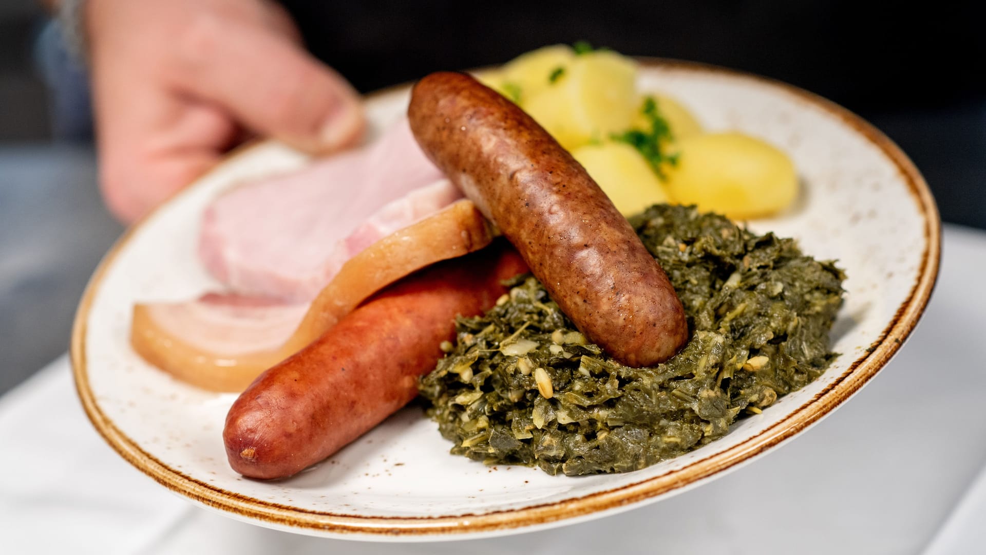 Eine Portion Grünkohl mit den traditionellen Beilagen Salzkartoffeln, Kochwurst, Pinkelwurst und Kasseler (Symbolbild): Die Bremer Gastro-Szene kommt in einem Ranking nicht gut weg.