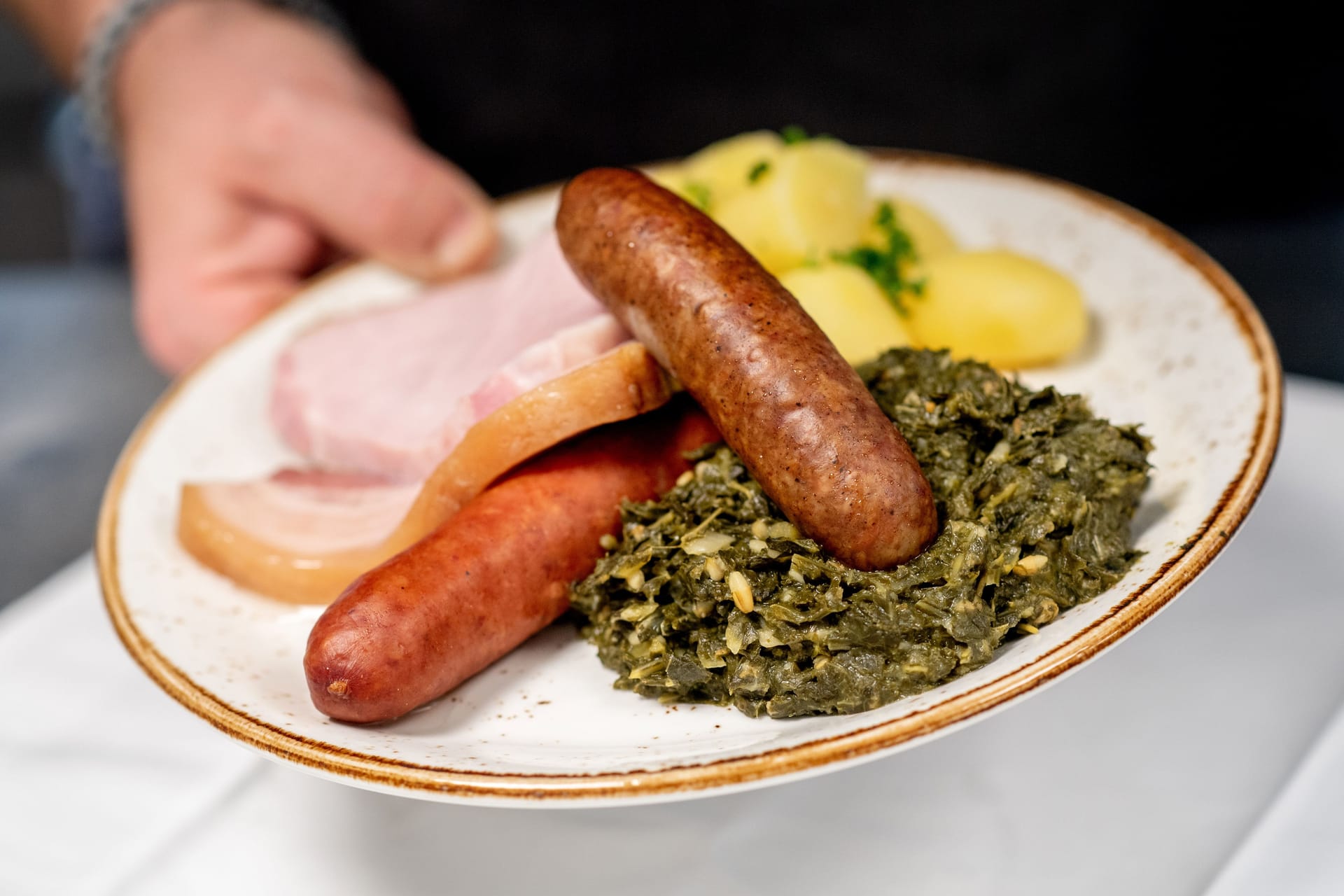 Eine Portion Grünkohl mit den traditionellen Beilagen Salzkartoffeln, Kochwurst, Pinkelwurst und Kasseler (Symbolbild): Die Bremer Gastro-Szene kommt in einem Ranking nicht gut weg.