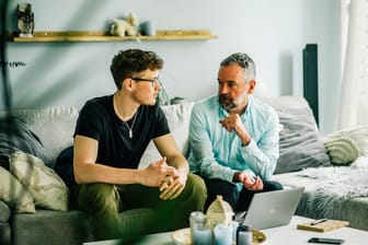 Vater und Sohn unterhalten sich im Wohnzimmer