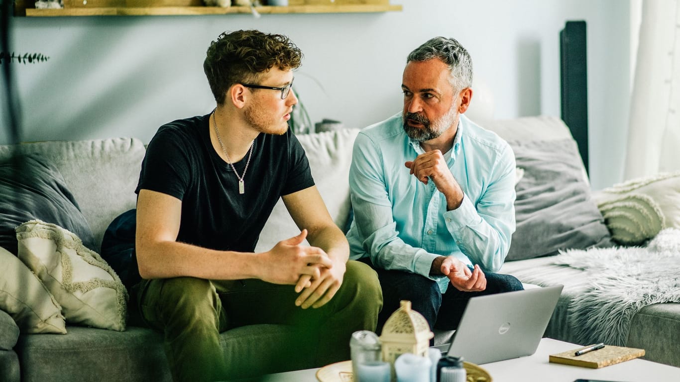 Vater und Sohn unterhalten sich im Wohnzimmer