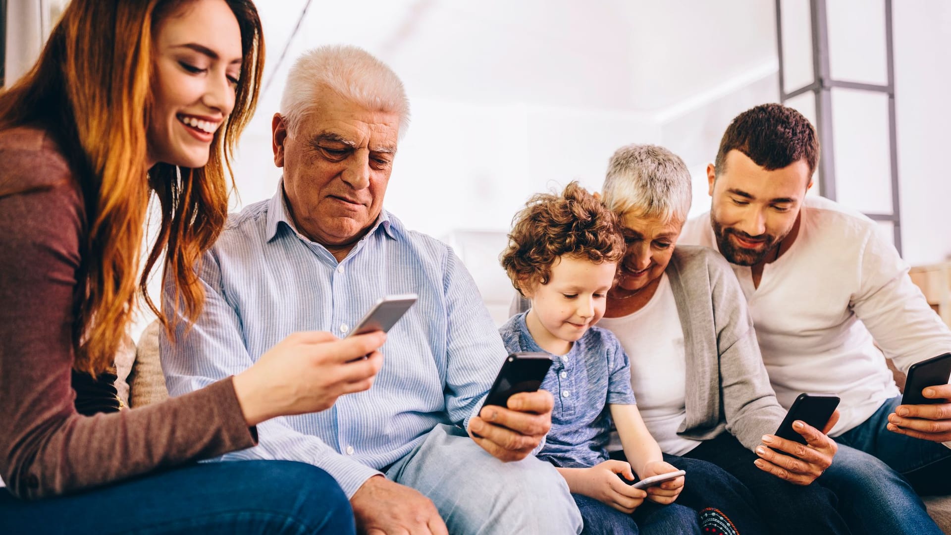 Drei Generationen einer Familie nutzen ihre Smartphones