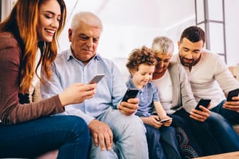 Drei Generationen einer Familie nutzen ihre Smartphones