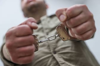 Ein Mann ist mit Handschellen gefesselt (Symbolbild): Der Täter hatte übers Internet Kontakt zu seinen Opfern aufgenommen.