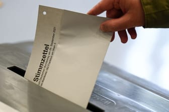 Stimmzettel wird in eine Wahlurne gesteckt