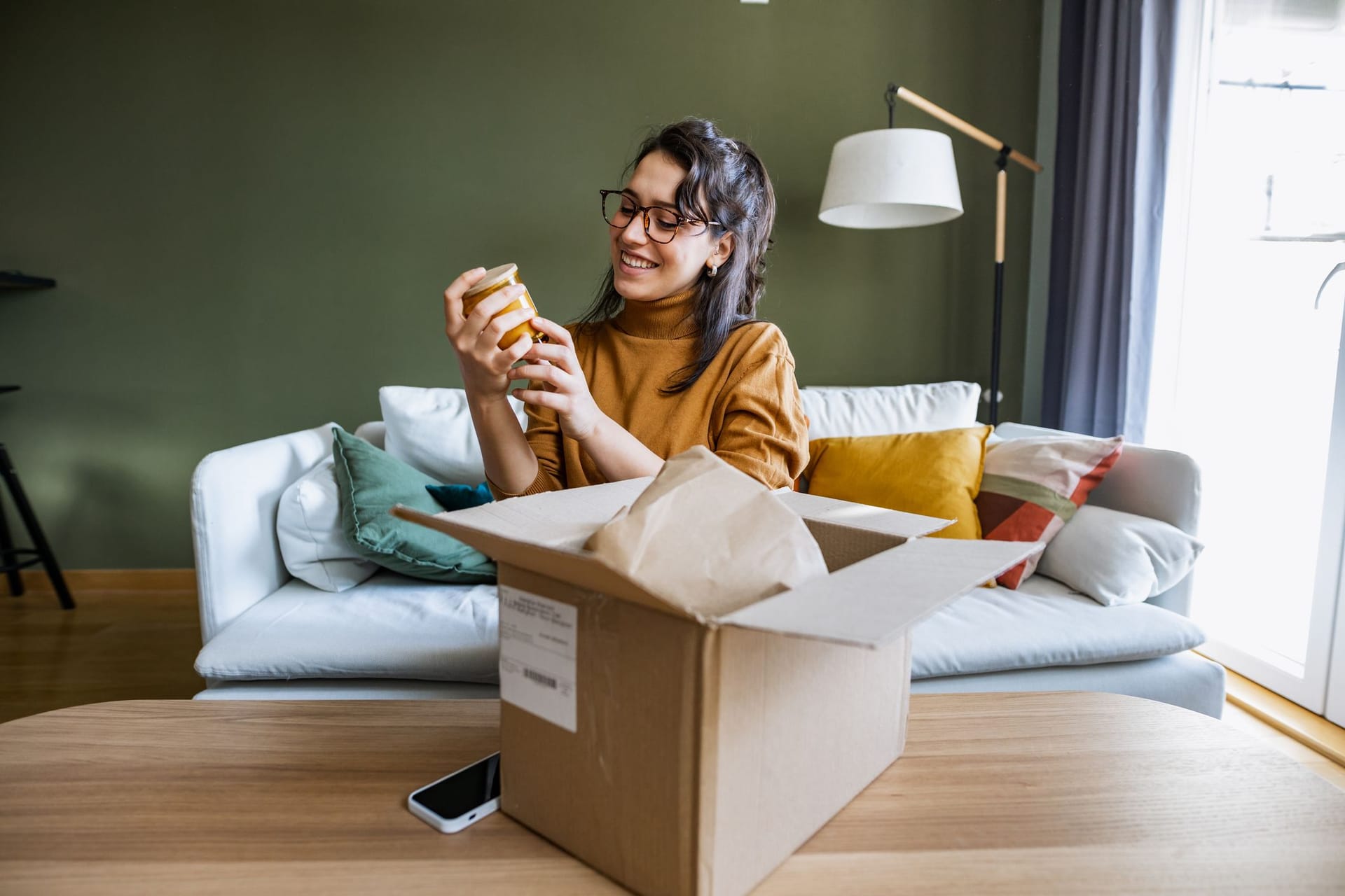 Frau packt Paket zu Hause aus