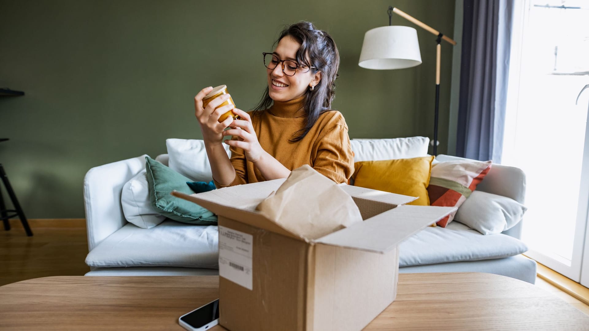 Frau packt Paket zu Hause aus