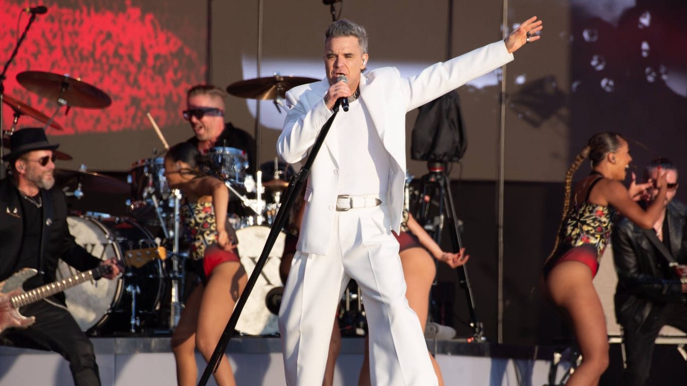 Robbie Williams singt auf der Bühne (Archivbild): Der Weltstar spielt 2025 ein Stadionkonzert in Hannover.