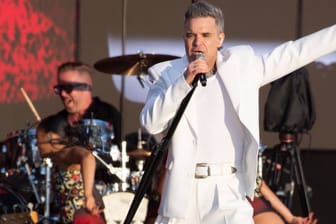 Robbie Williams singt auf der Bühne (Archivbild): Der Weltstar spielt 2025 ein Stadionkonzert in Hannover.