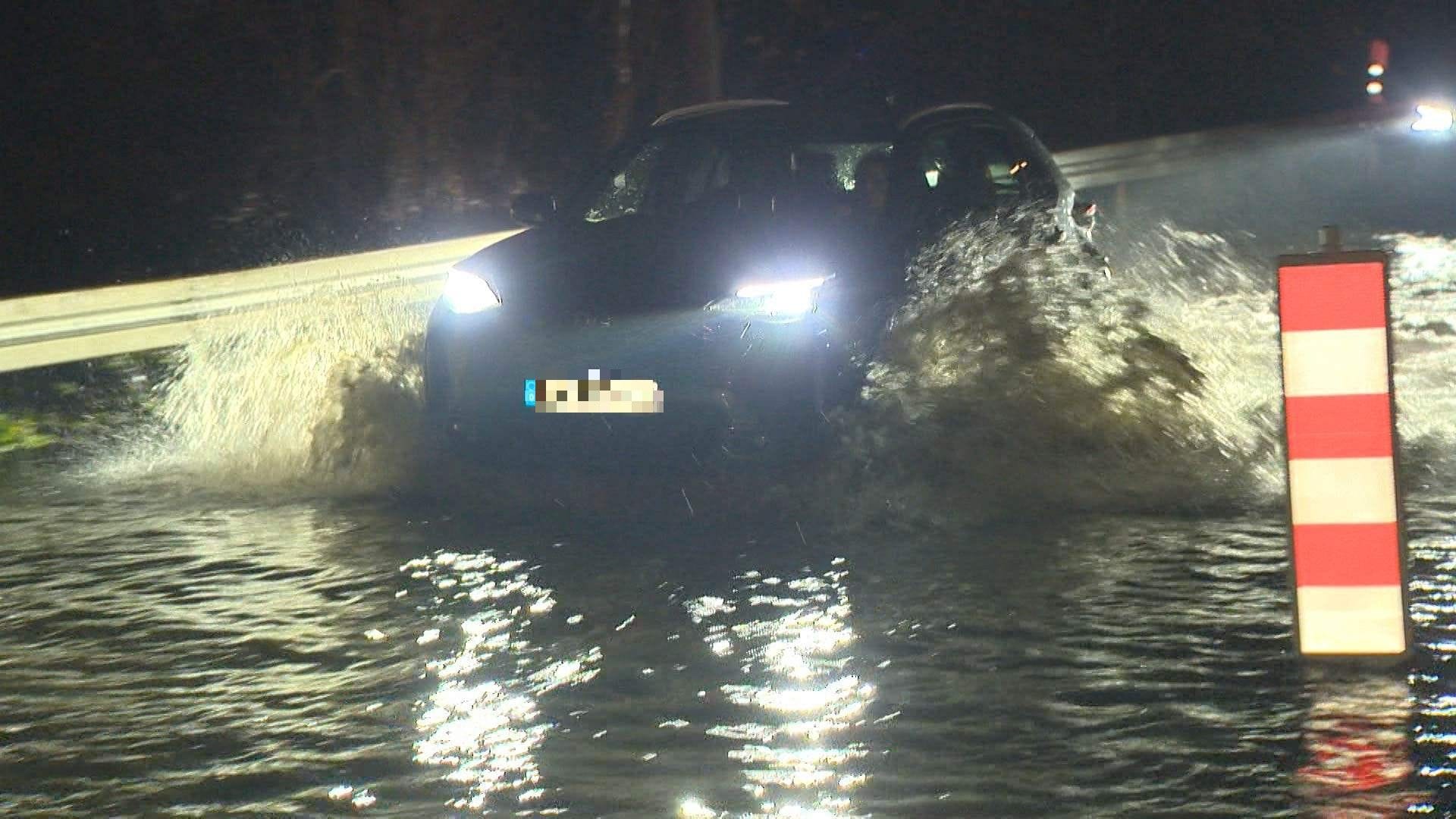 Autofahrer fährt durch das Hochwasser in Velbert.