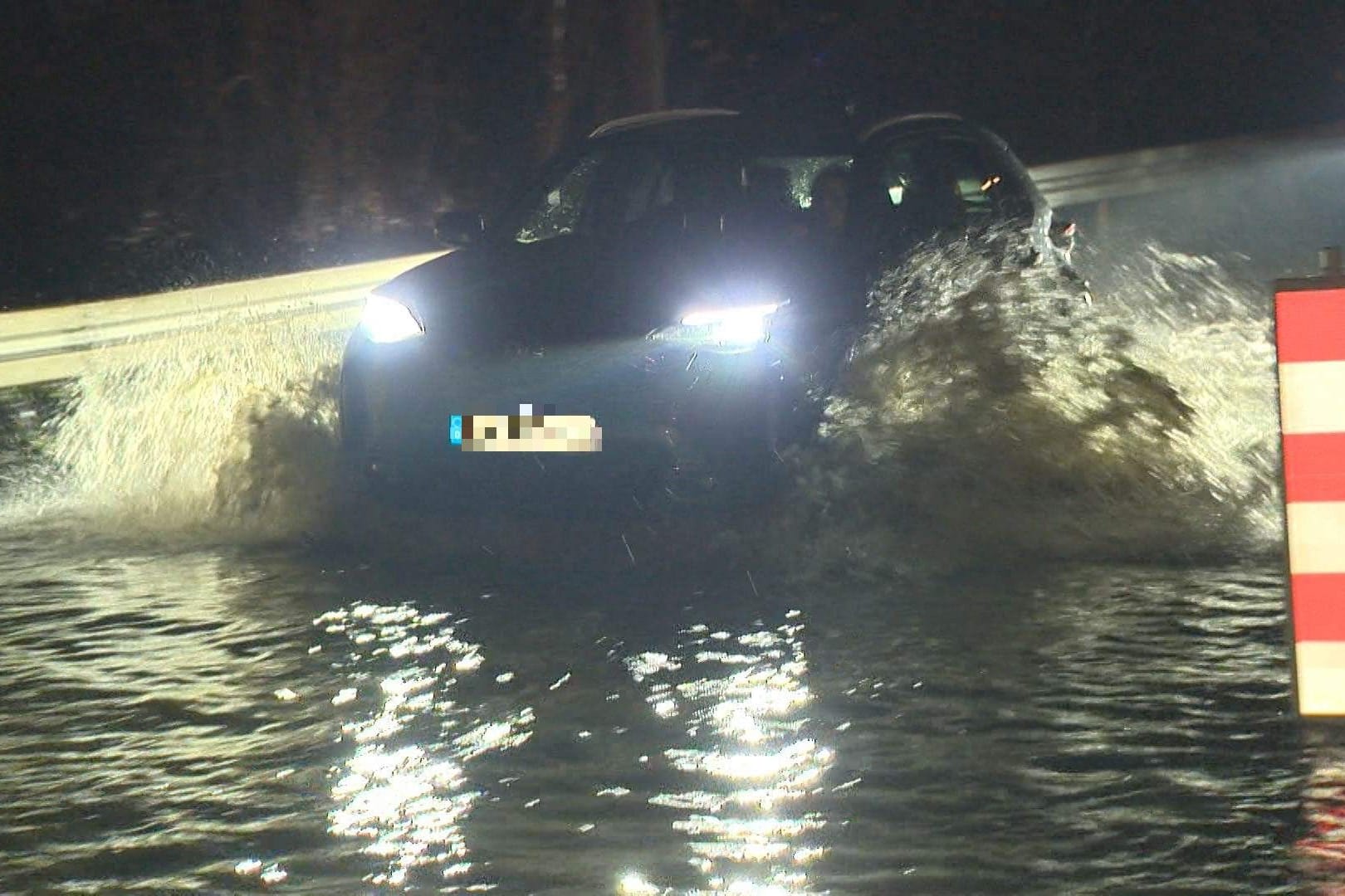 Autofahrer fährt durch das Hochwasser in Velbert.