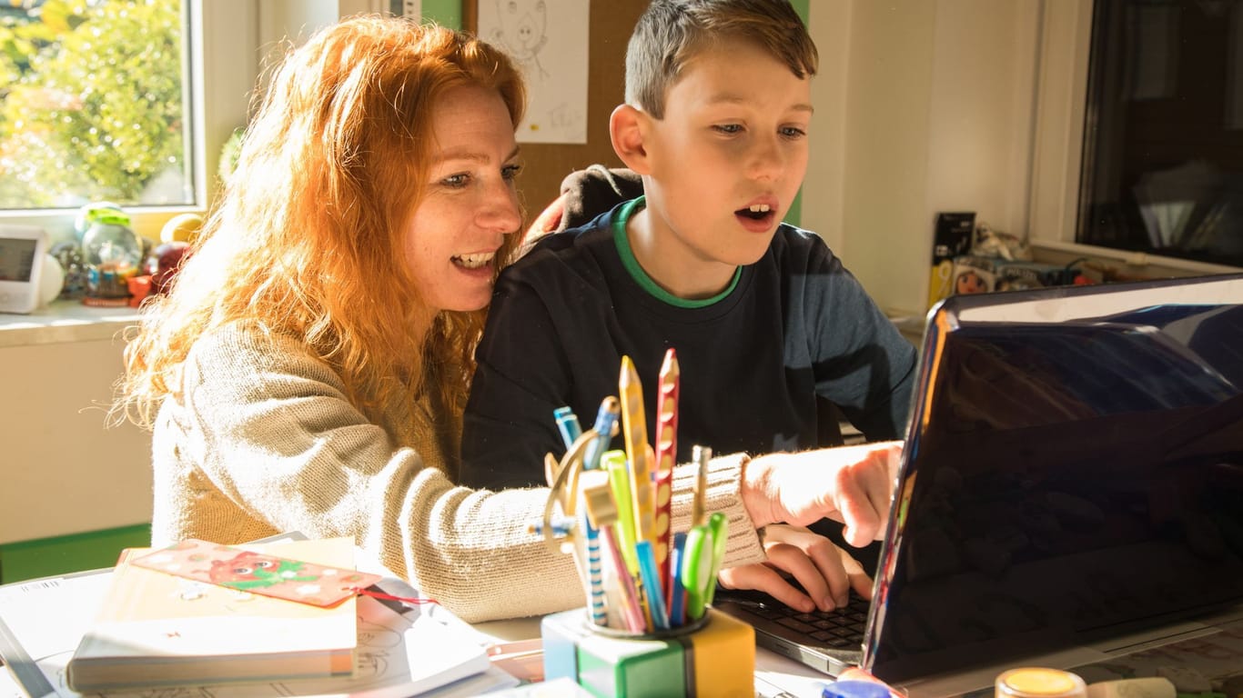 Mutter und Sohn sitzen gemeinsam vor einem Laptop