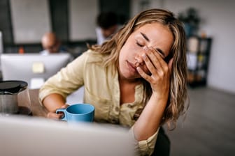 Frau sitzt am Arbeitsplatz und ist gestresst