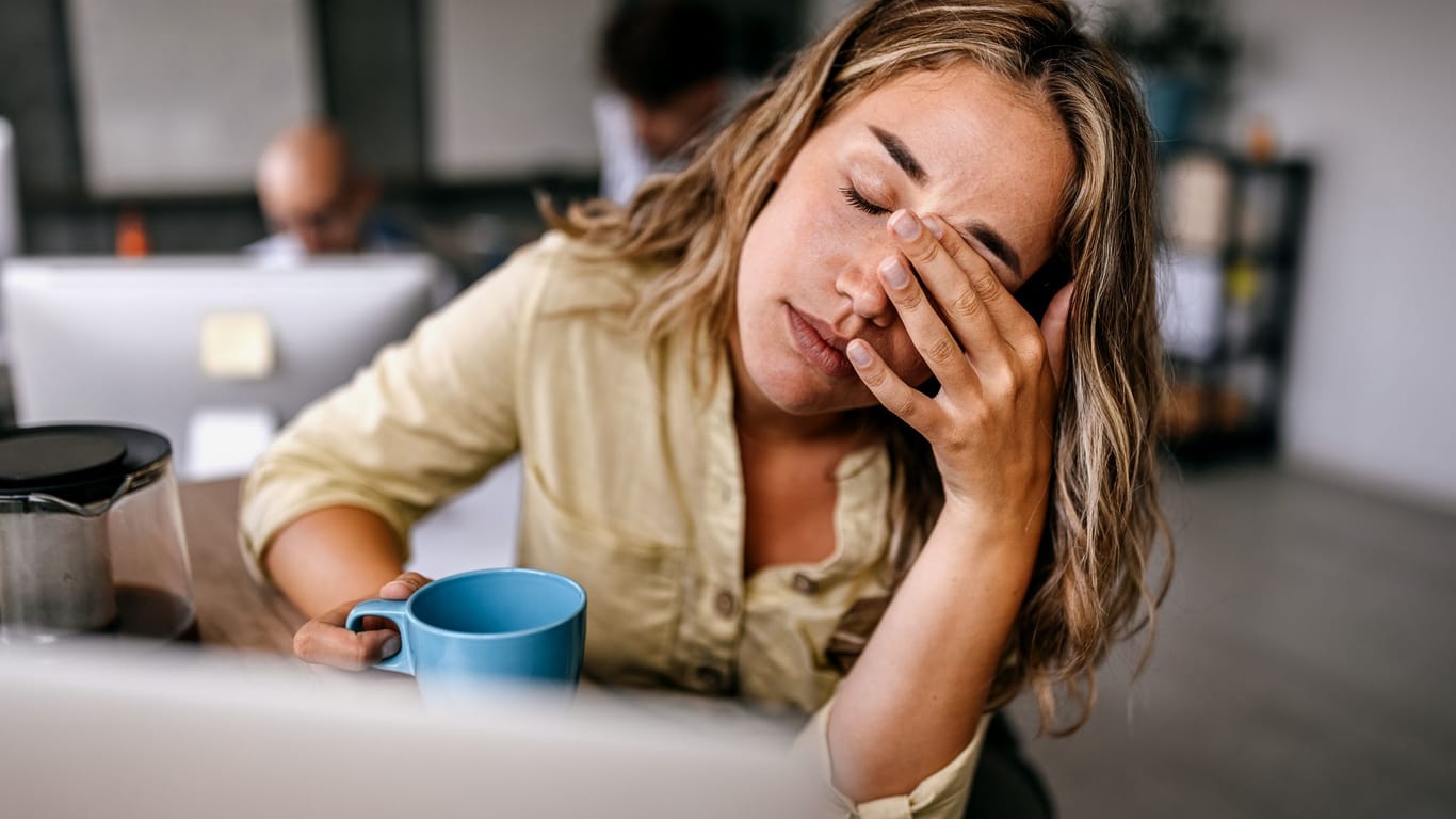 Frau sitzt am Arbeitsplatz und ist gestresst