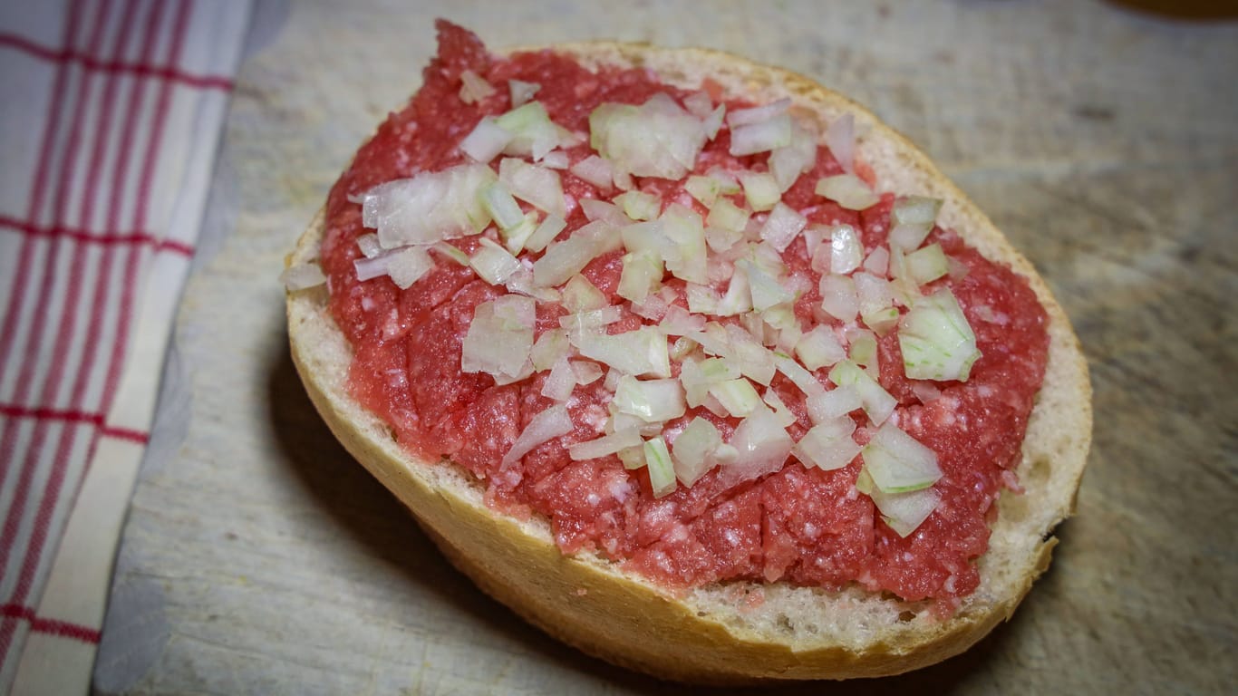 Ein klassisches Mettbrötchen (in Berlin heißt es Hackepeterbrötchen) mit rohen Zwiebeln. Liebhaber mögen es auch mit etwas Gewürzgurke.