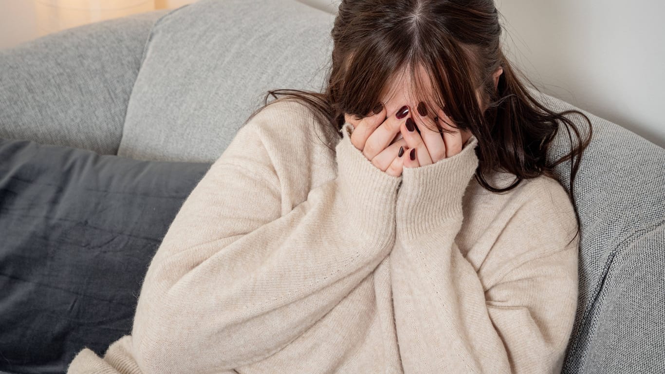 Eine Frau sitzt verängstigt auf einem Sofa (Symbolbild): Nach Fußballspielen ist die Gefahr, Opfer häuslicher Gewalt zu werden, besonders hoch.