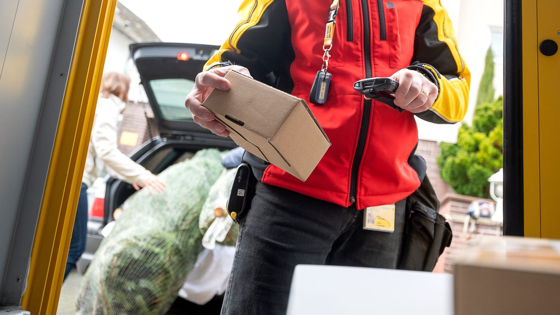 Ein DHL-Mitarbeiter scannt ein Paket für die Zustellung