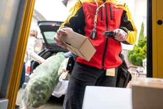 Ein DHL-Mitarbeiter scannt ein Paket für die Zustellung