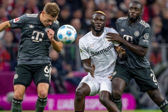 Leverkusens Victor Boniface (M.) im Duell mit Bayerns Joshua Kimmich (l.) und Dayot Upamecano: Das Pokalspiel wird in der ARD übertragen.