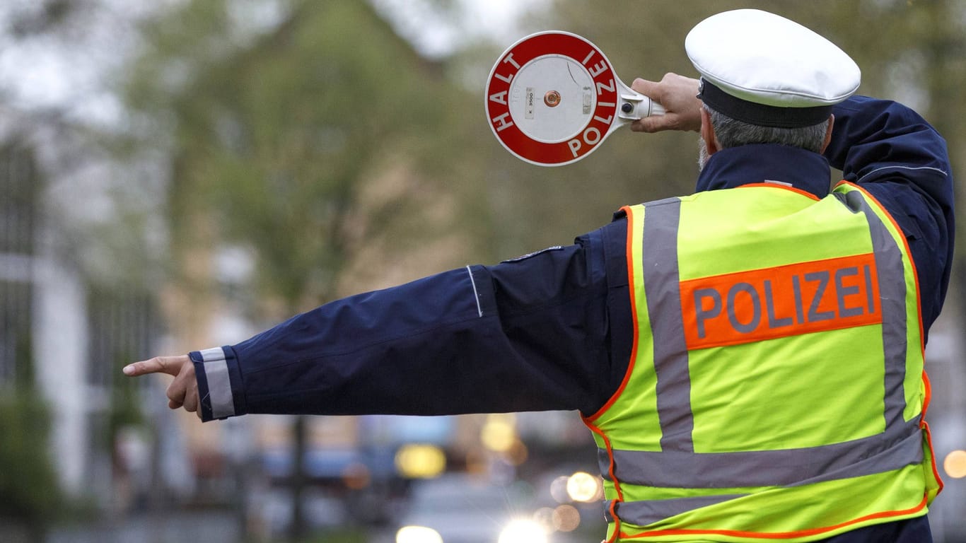 Ein Polizist winkt einen Autofahrer raus (Symbolbild)