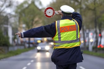 Ein Polizist winkt einen Autofahrer raus (Symbolbild)