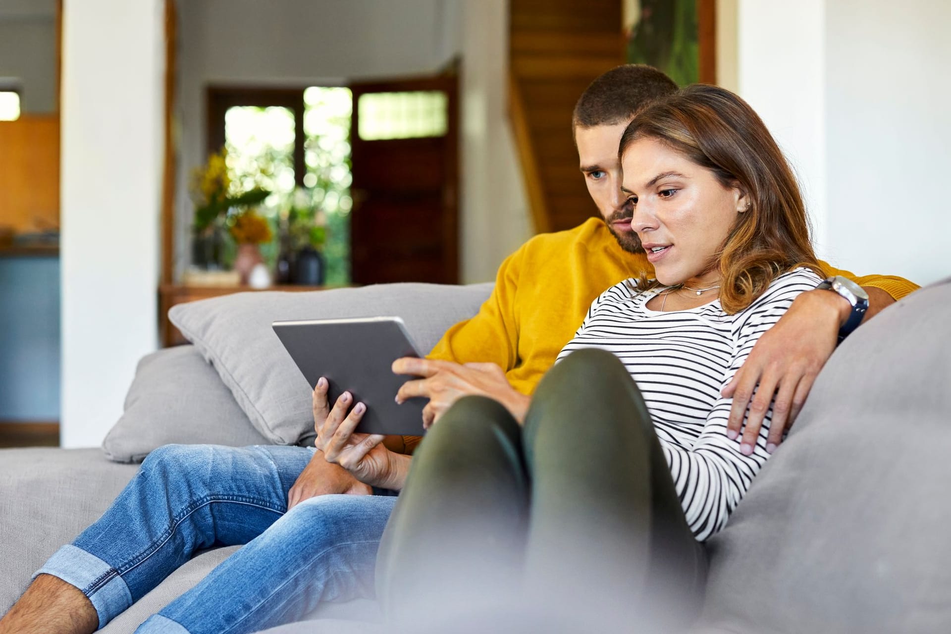 Ein Paar prüft etwas auf dem Tablet: Die Lohnabrechnung könnte 2025 etwas geringer ausfallen.