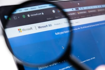 Microsoft 365 logo on the screen of laptop through magnifying glass