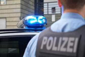 Polizist steht vor Polizeifahrzeug (Symbolbild): Die Staatsanwaltschaft Dresden hat die Ermittlungen gegen einen Polizisten eingestellt, der auf einer Feier den Hitlergruß gemacht haben soll.