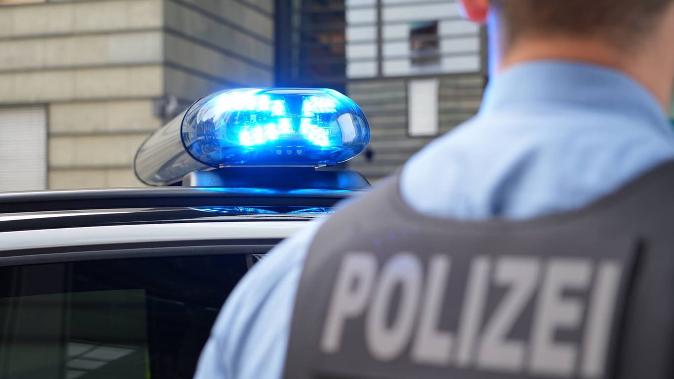 Polizist steht vor Polizeifahrzeug (Symbolbild): Die Staatsanwaltschaft Dresden hat die Ermittlungen gegen einen Polizisten eingestellt, der auf einer Feier den Hitlergruß gemacht haben soll.