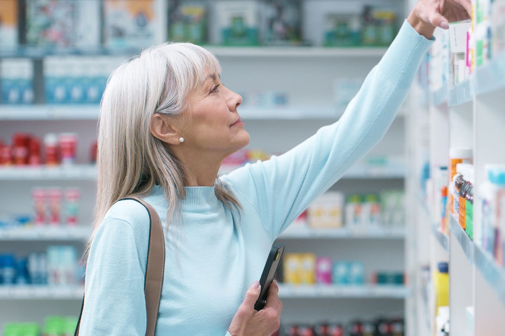 Eine Frau in der Apotheke greift nach einem Produkt aus dem Regal