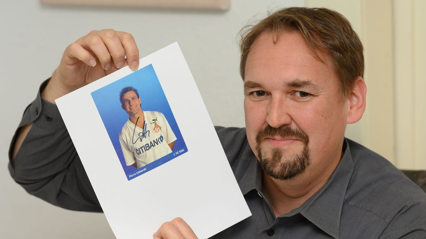 Christian Bach, Vorsitzender des Clubs der Autogrammsammler, hält ein Autogramm vom ehemaligen Fußball-Spieler Pierre Littbarski hoch.