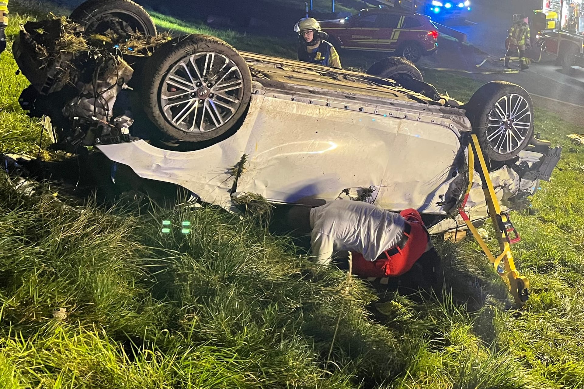 Feuerwehrleute stehen am zerstörten Unfallauto: Der Fahrer konnte sich nicht mehr selbst aus dem Wrack befreien.