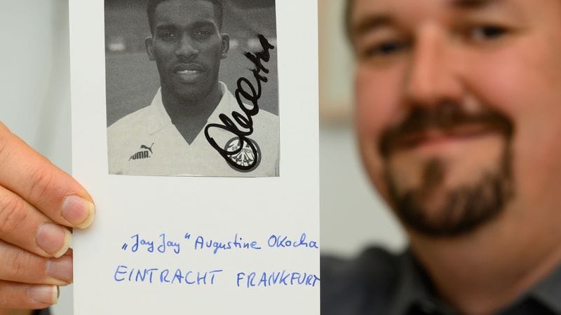 Christian Bach, Vorsitzender des Clubs der Autogrammsammler, hält ein Autogramm vom ehemaligen Fußball-Spieler Augustine Azuka „Jay-Jay“ Okocha.