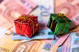 Miniaturweihnachtsgeschenke liegen auf Geldscheinen