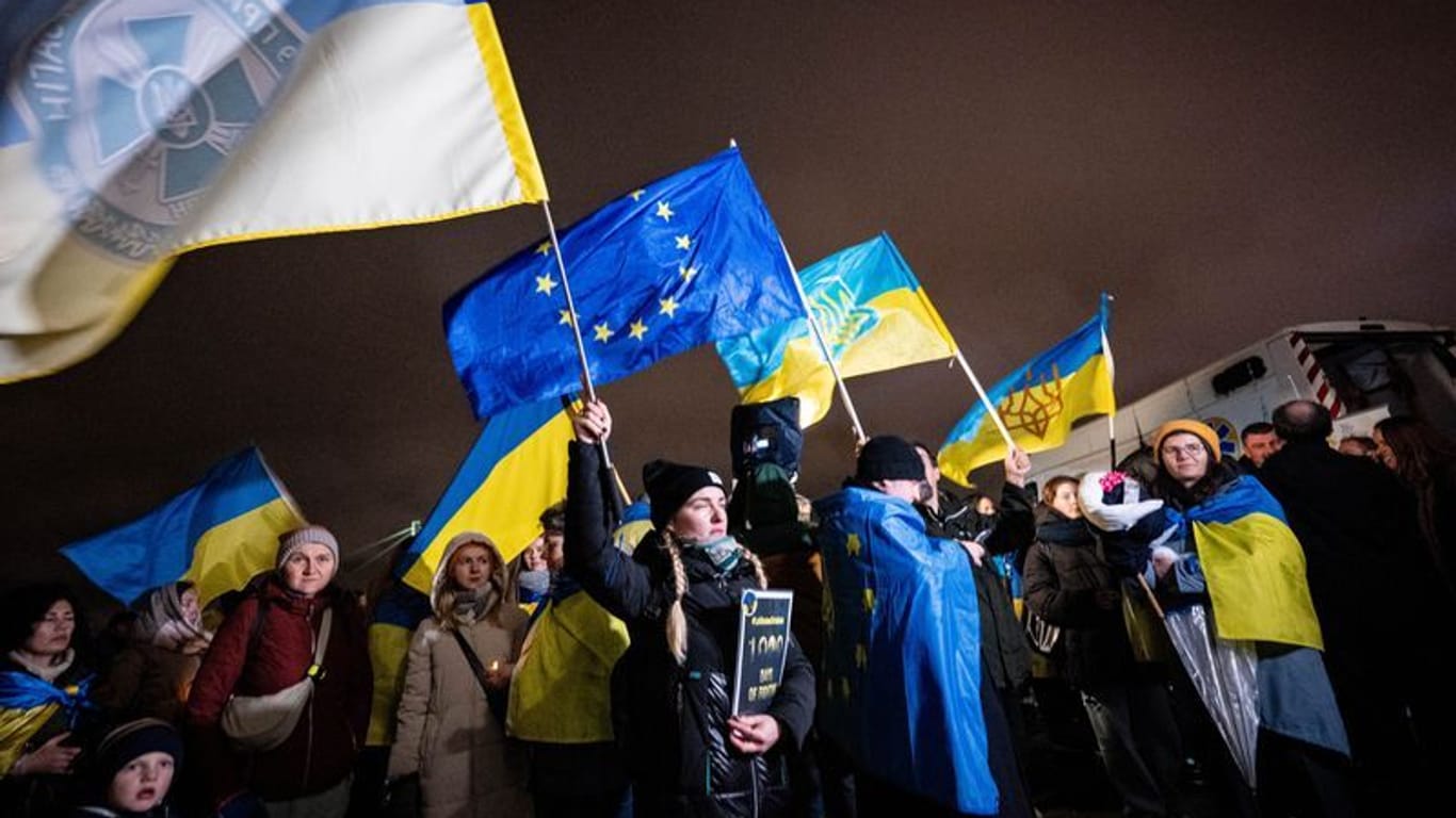 Teilnehmer der Solidaritätsdemonstration des deutsch-ukrainischen Vereins Blau-Gelbes Kreuz zu "1.000 Tage russische Vollinvasion" schwenken Fahnen.