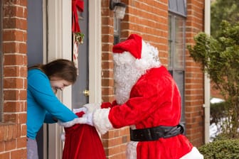 Ein Weihnachtsmann überreicht Geschenke: Die Arbeitsgentur sucht wieder Weihnachtsmänner.