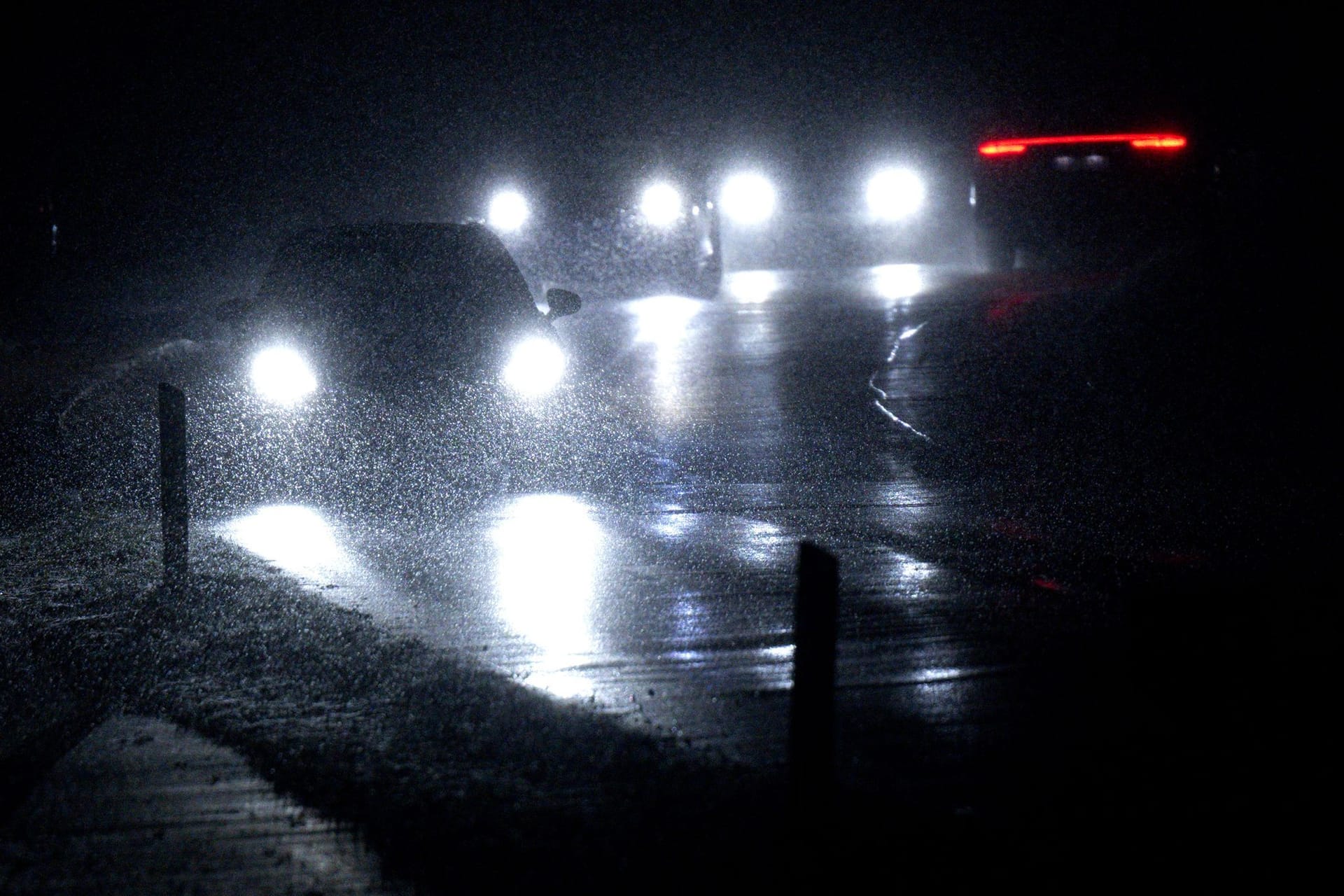 Autos fahren im Schneetreiben auf einer Straße in Bayern.