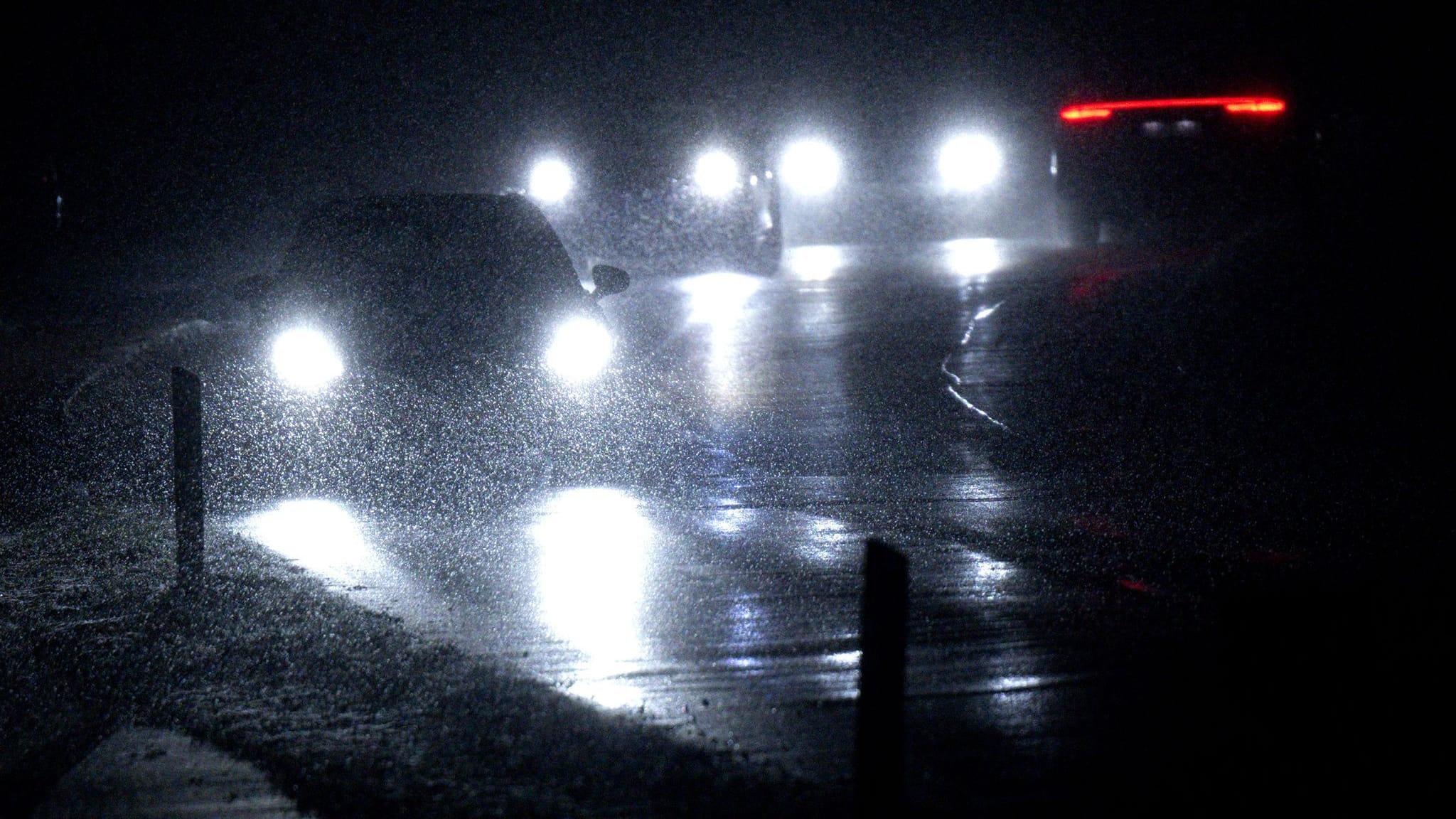 Autos fahren im Schneetreiben auf einer Straße in Bayern.