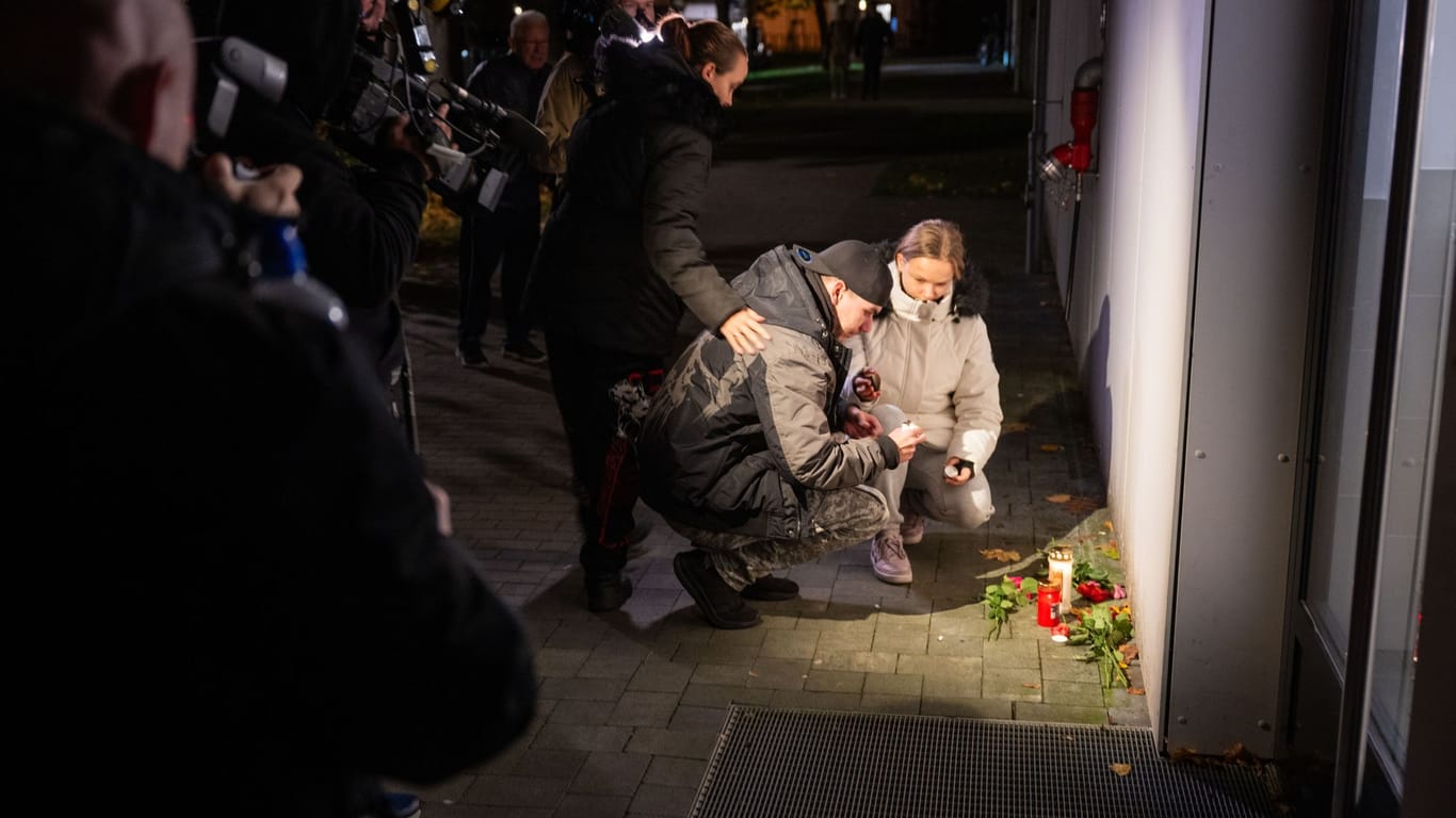 Menschen legen vor einem Mehrfamilienhaus in Berlin-Marzahn Blumen und Kerzen nieder. Die Mordkommission ermittelt wegen des Verdachts eines Tötungsdeliktes.