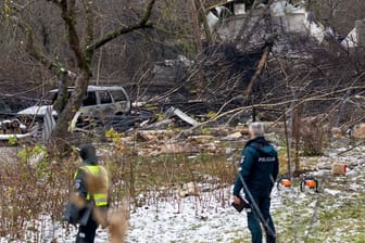 Mitarbeiter des litauischen Katastrophenschutzministeriums und Polizeibeamte stehen in der Nähe der Absturzstelle.