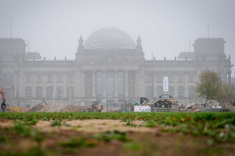 Das Reichstagsgebäude mit dem Bundestag ist am Morgen hinter einer Baustelle zu sehen.