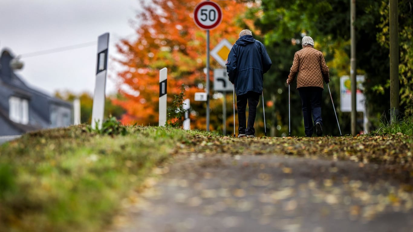 Zwei Senioren laufen auf einem mit Blättern bedeckten Weg